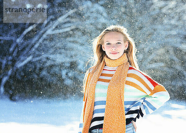 Fröhliches  schönes Teenager-Mädchen mit gelbem Schal draußen im Schnee.