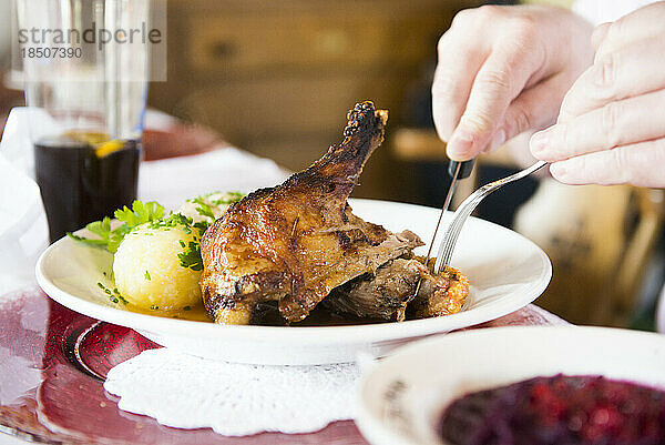 Mann isst Entenfleisch mit Kartoffelknödel am Tisch im Restaurant  Bayern  Deutschland