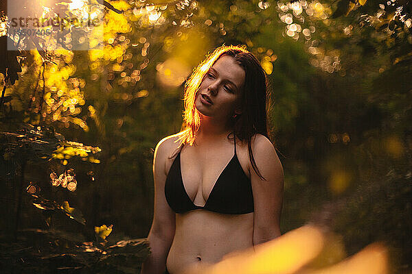 Junge Frau im Bikini steht im Wald