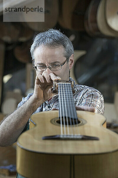 Handwerker untersucht Gitarre in der Werkstatt