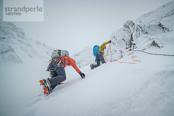 Männliche Bergsteiger beim Eisklettern bei Schnee und Frost