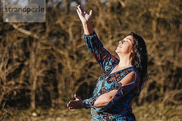 Eine Frau mit erhobenen Armen tanzt draußen mit Leidenschaft Flamenco