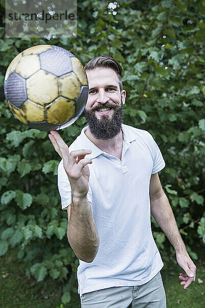 Junger Mann balanciert Fußball am Finger  Bayern  Deutschland