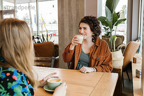 Zwei glückliche Frauen treffen sich drinnen zum Kaffeetrinken