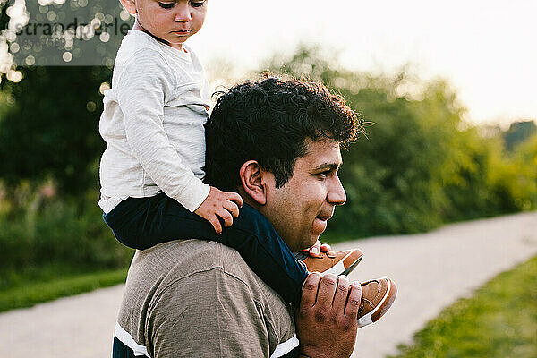 Papa trägt seinen Sohn bei Outdoor-Abenteuern und Wanderungen auf den Schultern