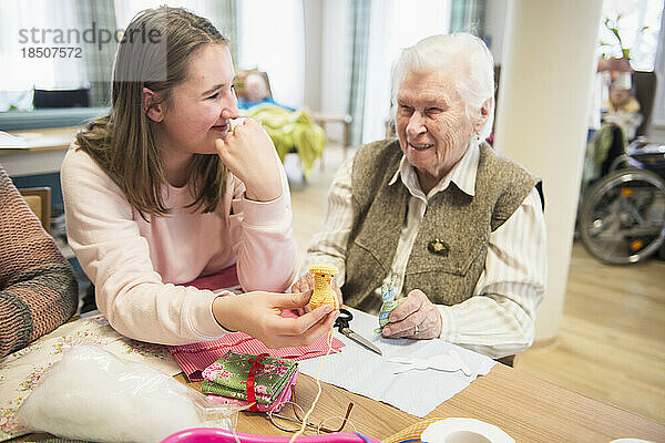 Ältere Frau mit Mädchen hält handgemachtes Häkelküken im Pflegeheim