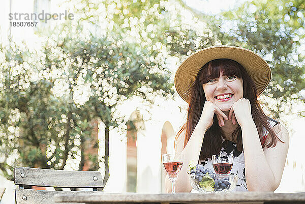 Schöne Frau mit Weingläsern und Trauben im Restaurant im Freien
