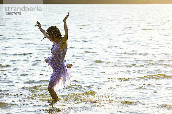 Frau im weißen Kleid tanzt im Wasser
