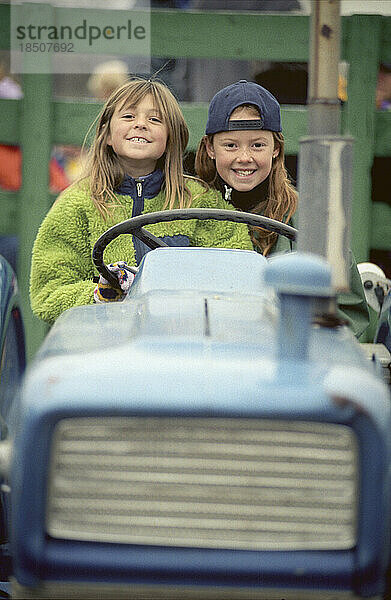 Zwei junge Mädchen auf einem Traktor.