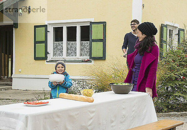 Familie bereitet einen Picknicktisch draußen im Bauernhaus vor  Bayern  Deutschland