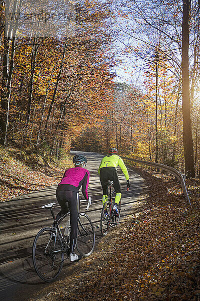 Paar fährt im Herbst mit dem Rennrad auf der Straße  Bayern  Deutschland