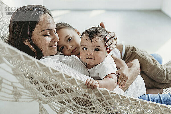 Mutter und kleines Mädchen und kleiner Sohn kuscheln in der Hängematte im Studio