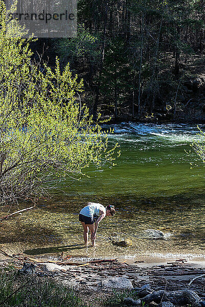Frau wäscht sich an sonnigen Sommertagen im klaren Flusswasser ab.