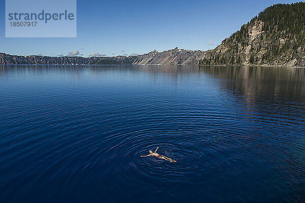 Ein junger Mann schwimmt im kalten  klaren Wasser des Crater Lake.