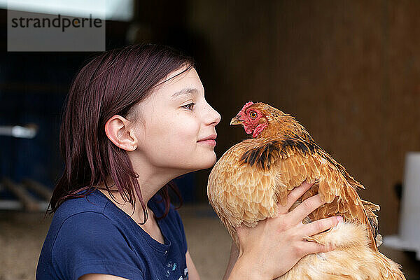 Mädchen von Angesicht zu Angesicht mit Henne im Hühnerstall