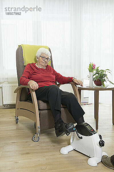 Ältere Frau macht Übungen auf einem Mini-Fußpedal-Trainingsgerät im Pflegeheim