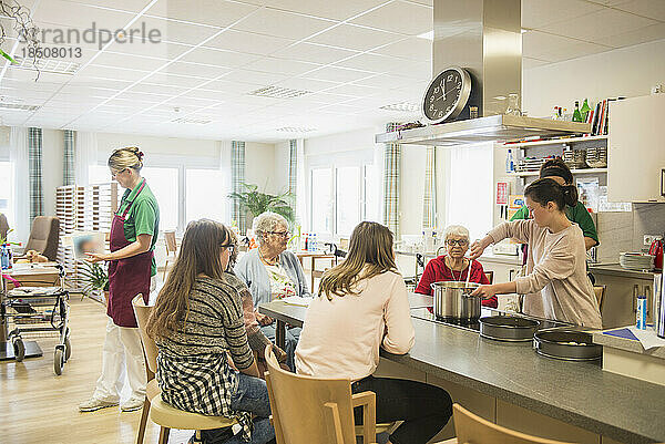 Krankenschwester mit älteren Frauen und Mädchen  die im Altenheim Essen zubereiten
