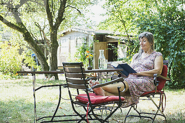 Ältere Frau liest ein Buch im Garten  Altötting  Bayern  Deutschland