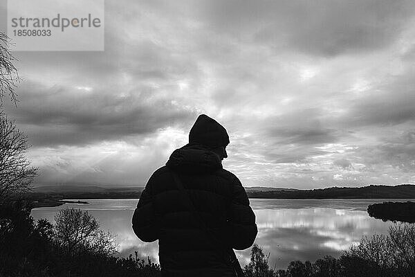 Silhouette einer Frau vor bewölktem Himmel und reflektierendem Wasser