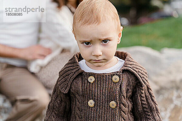Ein braunäugiges kaukasisches Kleinkind in einem braunen Strickpullover