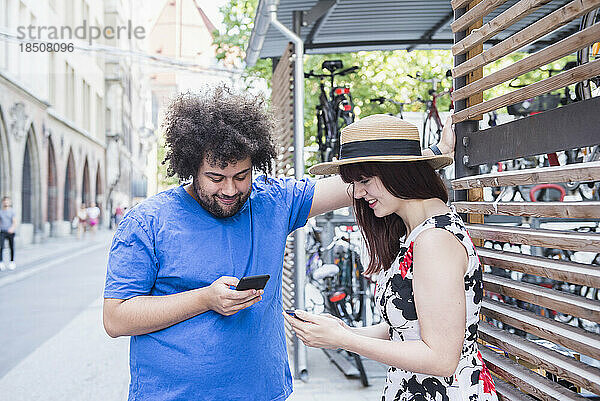 Junges Paar schreibt Textnachrichten auf dem Mobiltelefon in der Stadt