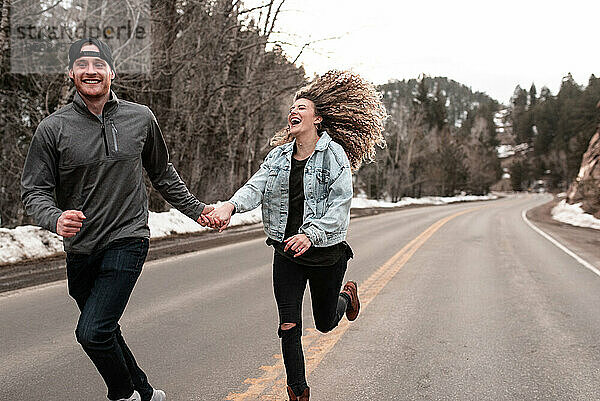 Abenteuerlustiges Paar läuft im Winter entlang der Straße in den Colorado Mountains