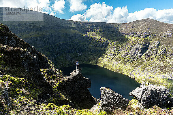 Bergsteigermann steht oben auf dem Coumshingaun-See in Irland