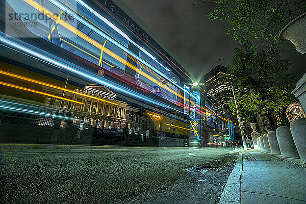 Langzeitbelichtung der Lichter eines Stadtbusses  der am State House-Gebäude vorbeifährt.