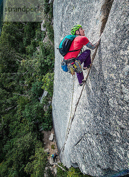Mann klettert steilen Riss an der Felswand
