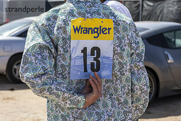 Ein Rodeo-Teilnehmer passt seine Nummer hinter der Bühne bei einem schwarzen Rodeo an
