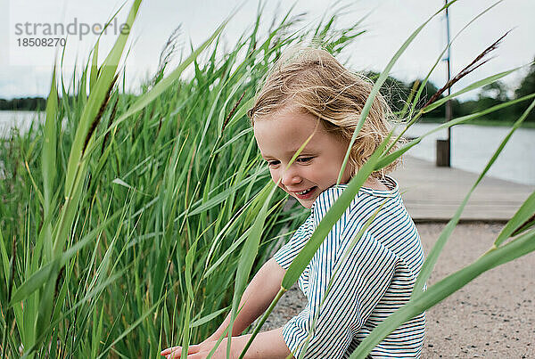 Porträt eines lächelnden jungen Mädchens  das im Sommer am Strand sitzt