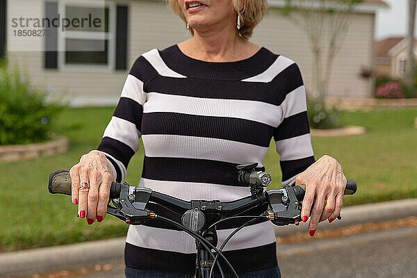 Reife Frau in den Siebzigern genießt einen Tag draußen auf ihrem Fahrrad.