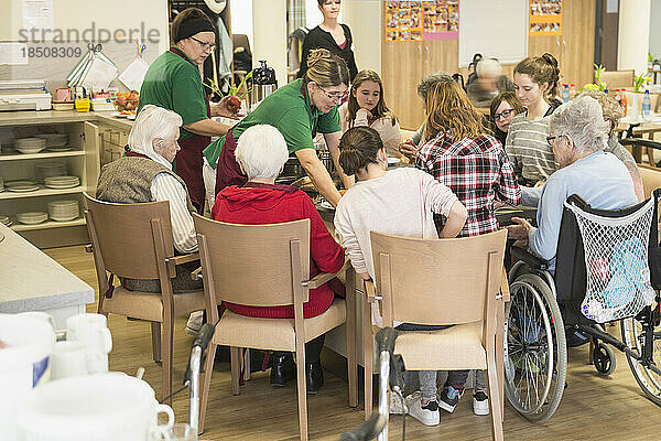 Pflegepersonal mit älteren Frauen und Mädchen bereitet im Seniorenheim Essen zu