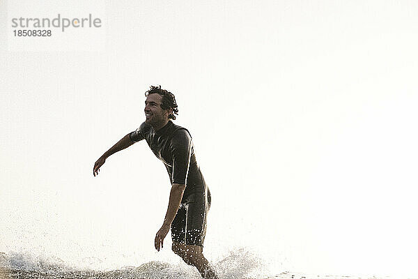 Profi-Surfer Vicente Romero lächelt  während er bei Sonnenuntergang aus einer Welle springt