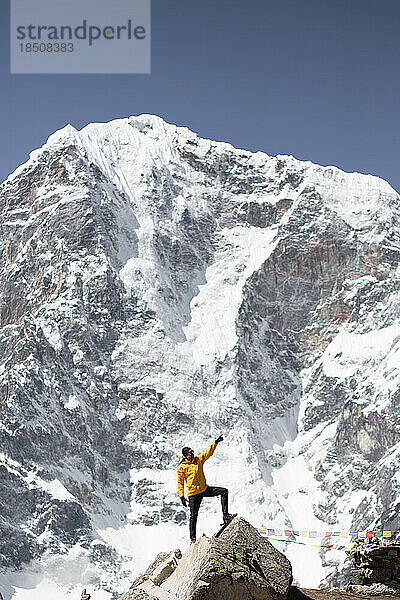 Ein Mann posiert unter den Bergen auf dem Everest Base Camp Trek.