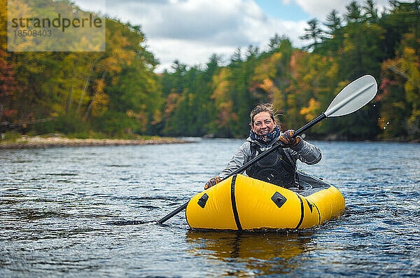 Frau lächelt und lacht  während sie mit Packraft auf dem Fluss paddelt