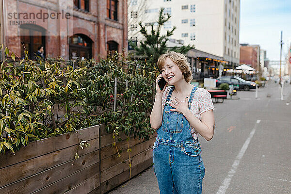 Glückliche Frau telefoniert beim Spaziergang durch die Innenstadt