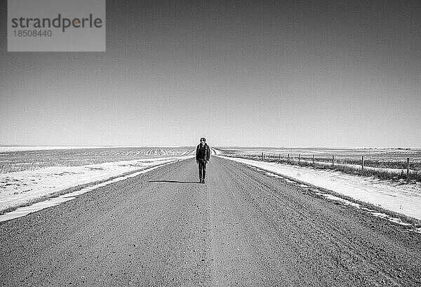 Der Mann steht einsam auf einer einsamen Schotterstraße in Kansas