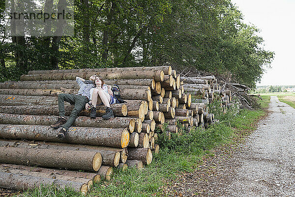 Junges Paar ruht auf einem Holzstapel in einem Wald  Bayern  Deutschland
