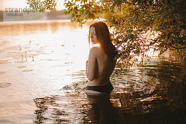 Junge sinnliche Frau im See bei Sonnenuntergang