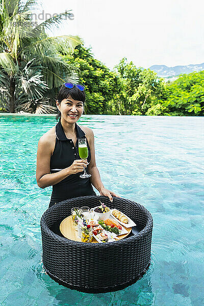 Schöne Frau genießt ein schwimmendes Frühstück in Thailand