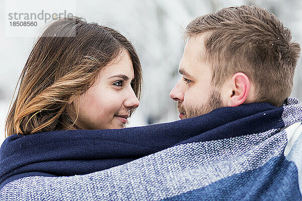 Liebespaar ist in einen blauen Schal gehüllt  inmitten des Snowparks