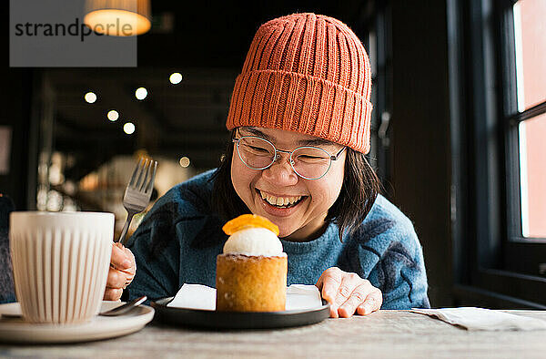 Asiatische Frau lächelt ihren Cupcake in einem Café an