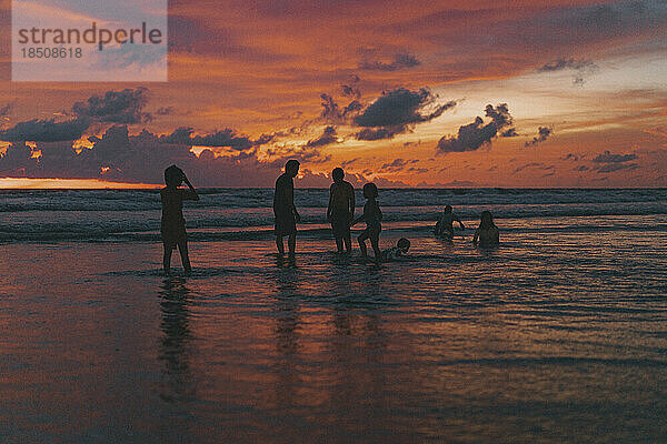 Kinder spielen bei Sonnenuntergang am Strand am Meer. Bali  Indonesien