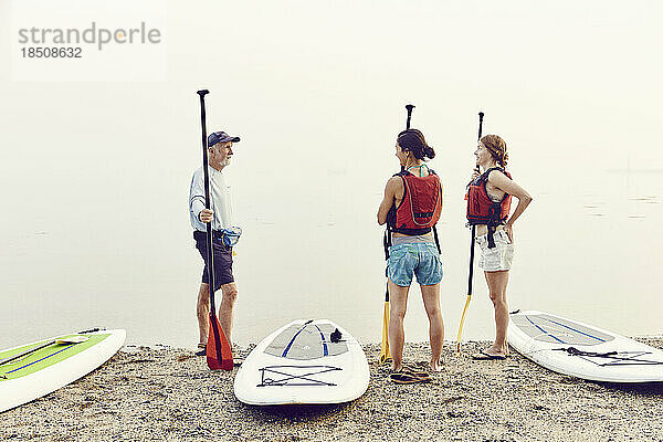 Eine Gruppe von Freunden bereitet sich im Nebel auf ein Standup-Paddle-Board-Abenteuer vor