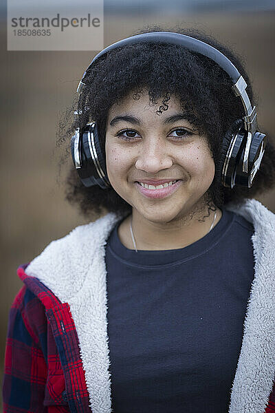 biraziales Teenager-Mädchen  das Kopfhörer trägt und lächelt