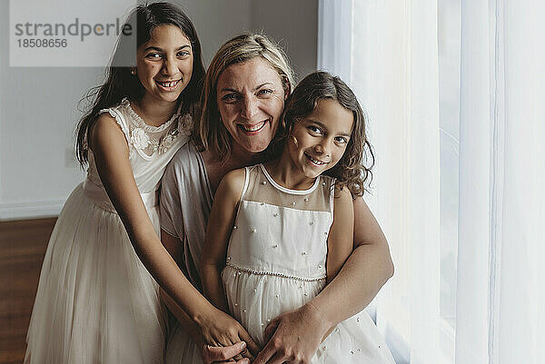 Porträt einer Mutter und ihrer Töchter  die im Studio in die Kamera lächeln