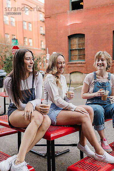 Freunde lachen  während sie mit Kaffee am Picknicktisch sitzen