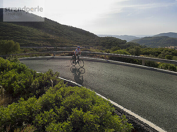 Frau fährt bei Sonnenuntergang mit dem Fahrrad gegen den Berg
