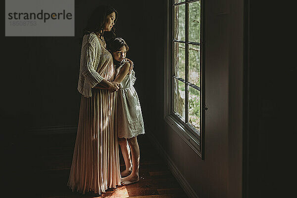 Mutter und Tochter umarmen sich und schauen aus dem Studiofenster